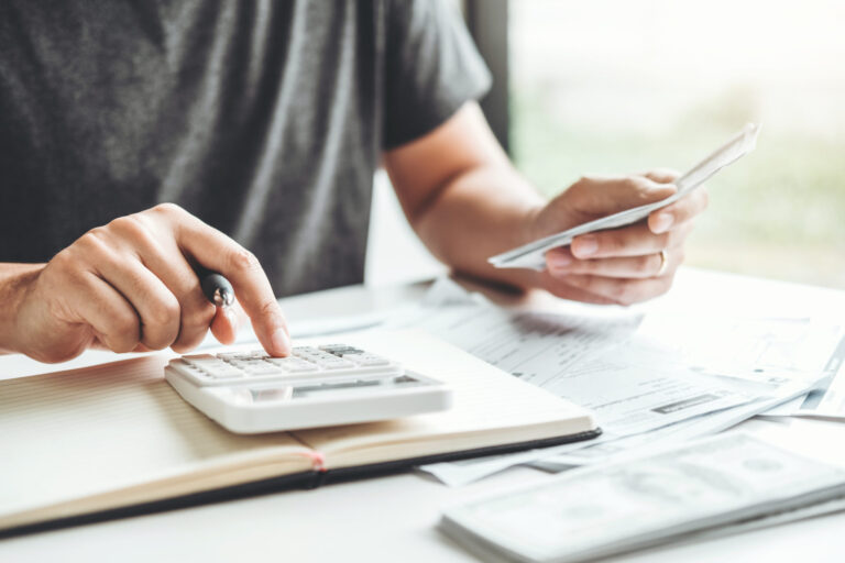 une personne calculant des frais sur une calculatrice